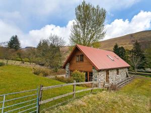 a small house in a field with a fence at The Barn - S4593 in Lochearnhead