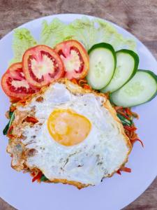a plate of food with an egg and tomatoes and lettuce at bucu hidden guest house, and meditation center in Payangan +37 photos