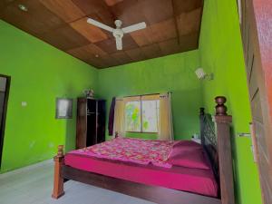 a green bedroom with a bed with a ceiling fan at bucu hidden guest house, and meditation center in Payangan