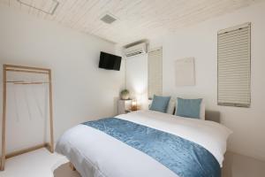 Un dormitorio blanco con una cama grande con almohadas azules. en Ocean Front Villa Ishigakijima Ⅲ, en Ishigaki Island 37 fotos más