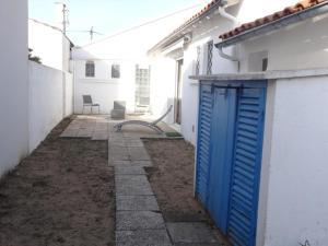 a blue door in the side of a white building at Maison confortable près de la plage, au calme, idéale pour des vacances en famille - FR-1-476-101 in La Faute-sur-Mer