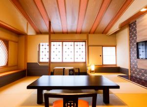 een kamer met een tafel en stoelen en een raam bij Onishiya Suishoen in Toyooka