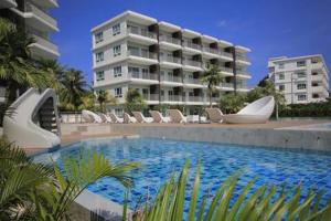 a swimming pool with white chairs and a building at The Sea Condominium in Sam Roi Yot