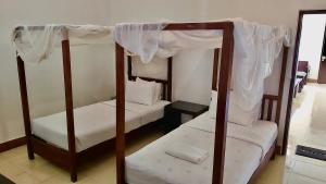 a bedroom with two bunk beds with white sheets at Aman Gati Hotel Lakey in Huu