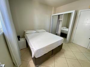 ein kleines Schlafzimmer mit einem Bett und einem Spiegel in der Unterkunft Apartamento Estúdio Vista Mar in Balneário Camboriú