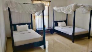 a bedroom with two bunk beds with white sheets at Aman Gati Hotel Lakey in Huu