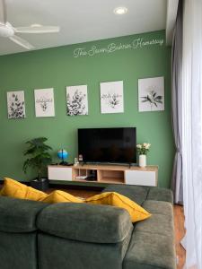 a green living room with a couch and a television at TheSevenBahrin Homestay in Seri Kembangan