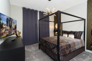 ein Schlafzimmer mit einem schwarzen Himmelbett und einem Flachbild-TV in der Unterkunft Gorgeous 6 Bd SF Close to Disney w/ Pool @ Champions Gate Resort 712 in Kissimmee