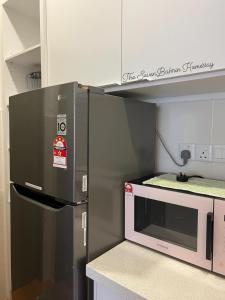 a kitchen with a refrigerator and a microwave at TheSevenBahrin Homestay in Seri Kembangan