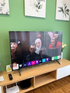 a large flat screen tv sitting on a wooden stand at TheSevenBahrin Homestay in Seri Kembangan