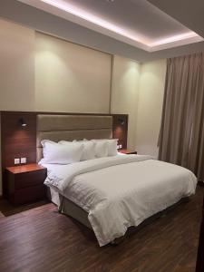 een slaapkamer met een groot bed met witte lakens en kussens bij جراند أفيكس 2 للشقق المخدومة - GRAND AFFIX 2 in Riyad