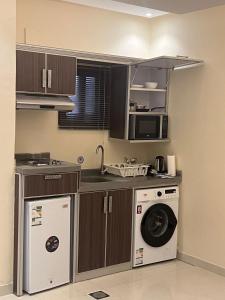 een keuken met een wasmachine en een magnetron bij جراند أفيكس 2 للشقق المخدومة - GRAND AFFIX 2 in Riyad