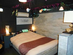 une chambre avec un lit et un mur de briques dans l'établissement Abollo Odawara, à Odawara