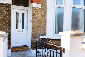 a white door on a brick house with a bench at Amazing 3bedroom ground floor house with garden and 2 bathrooms in London