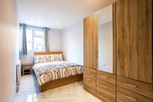 ein Schlafzimmer mit einem Bett und einem großen Holzschrank in der Unterkunft Amazing 3bedroom ground floor house with garden and 2 bathrooms in London