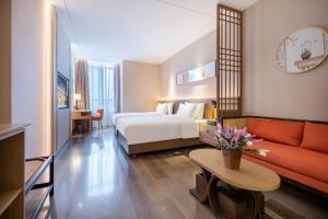 Rezen Longuu Hotel - Universiade Center Longgang Shenzhen في Longgang: غرفه فندقيه بسرير واريكه