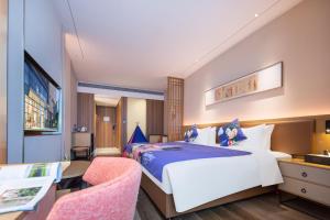 um quarto de hotel com uma cama grande e uma secretária em Rezen Longuu Hotel - Universiade Center Longgang Shenzhen em Longgang