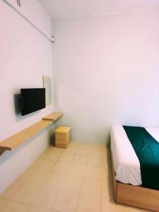 ein Schlafzimmer mit einem Bett und einem TV an der Wand in der Unterkunft Homestay 81 Batu Batam in Nagoya
