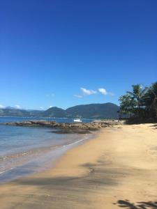 uma praia arenosa com palmeiras e o oceano em Angra dos Reis - Casa pé na areia na Praia de Fora - Ponta Leste em Angra dos Reis