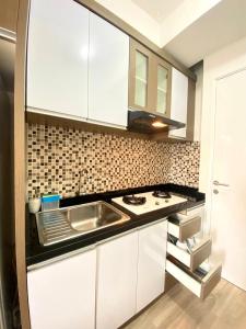 a kitchen with white cabinets and a sink at Apartemen Pakubuwono Terrace Tipe Studio Jakarta in Jakarta