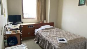 a bedroom with a bed and a desk and a window at Hotel Portside Imabari in Imabari