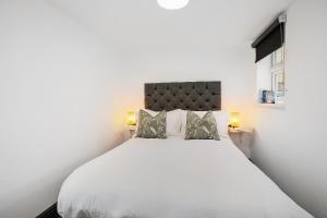a bedroom with a white bed with two lamps at TYME Coastal Suites-1 and 2 Bedroom in Cleethorpes