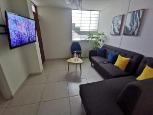 uma sala de estar com um sofá e uma televisão em Cómodo departamento céntrico y cerca a lugares turísticos de la ciudad em Arequipa