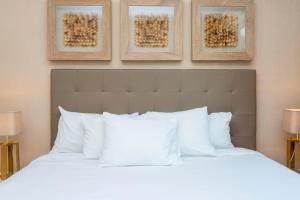 um quarto com uma cama branca com três fotografias na parede em Stunning 4Bd Close to Disney @ Magic Village 7614 em Orlando