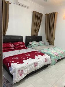 two beds sitting in a room with curtains at JRK HOMESTAY A in Jertih