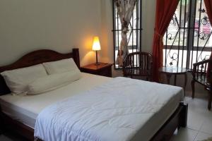 a bedroom with a white bed with two chairs and a window at T'Rai Homestay in Dungun