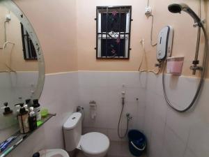 a bathroom with a shower and a toilet and a mirror at T'Rai Homestay in Dungun