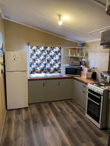 cocina con nevera, fogones y ventana en Central on Shenton en Geraldton