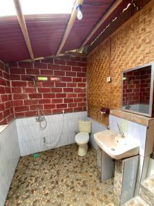 a brick bathroom with a toilet and a sink at Tetebatu Sama Sama Bungalows in Tetebatu