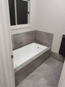 een badkamer met een wit bad en een raam bij Olley's Place in Wellington East