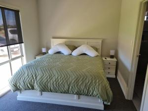 a bedroom with a bed with two pillows and a window at Olley's Place in Wellington East