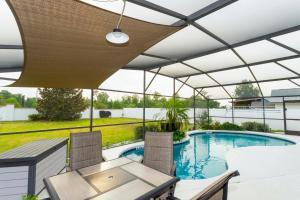 a patio with a table and chairs and a swimming pool at Charming 3Bd w/ Pool Close to Disney @ 7826 Indian Ridge in Orlando