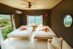 two beds in a room with a view of the ocean at Vacation House Familia in Kōzushima