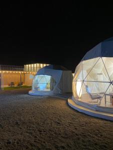 two tents are set up in a field at night at Bidiyah Domes in Badīyah
