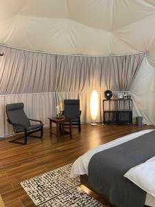 a bedroom with a bed and chairs and a tent at Bidiyah Domes in Bidiyah