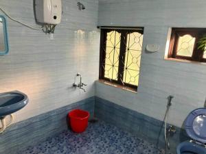 ein Badezimmer mit einem Waschbecken und einem roten Eimer in der Unterkunft Ashpil House Guest House Margao South Goa in Navelim