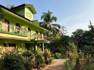 ein grünes Gebäude mit einem Balkon und Palmen in der Unterkunft Ashpil House Guest House Margao South Goa in Navelim