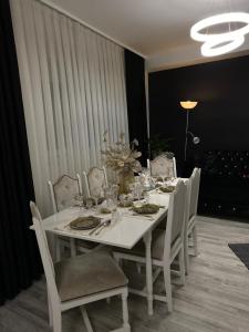 een witte eettafel met stoelen en een wit tafelkleed bij Vila CCC in Oradea
