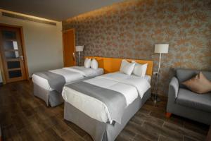 une chambre d'hôtel avec deux lits et une chaise dans l'établissement Sama Muscat Hotel, à Al Khawḑ