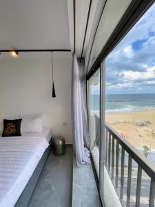 a bedroom with a bed and a balcony with the beach at Orchid sea view apartment in Tel Aviv
