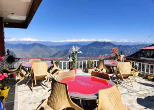 un patio con mesa, sillas y montañas en Hotel Mount View Dhanaulti Dreams en Dhanaulti