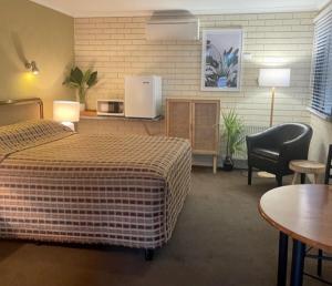 Habitación de hotel con cama, mesa y sillas en Estelle Kramer Motel, en Armidale