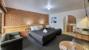 a hotel room with a bed and a brick wall at The Cottage Motor Inn Albury CBD in Albury