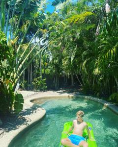 a man sitting on a raft in a swimming pool at Sandpipers Beach House in Palm Cove