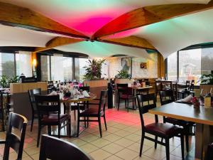 un restaurante con mesas y sillas y techo rosa en Hotel Lacotel en Avenches