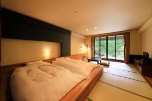 a bedroom with a large bed and a large window at Hotel Shikisai in Nikko